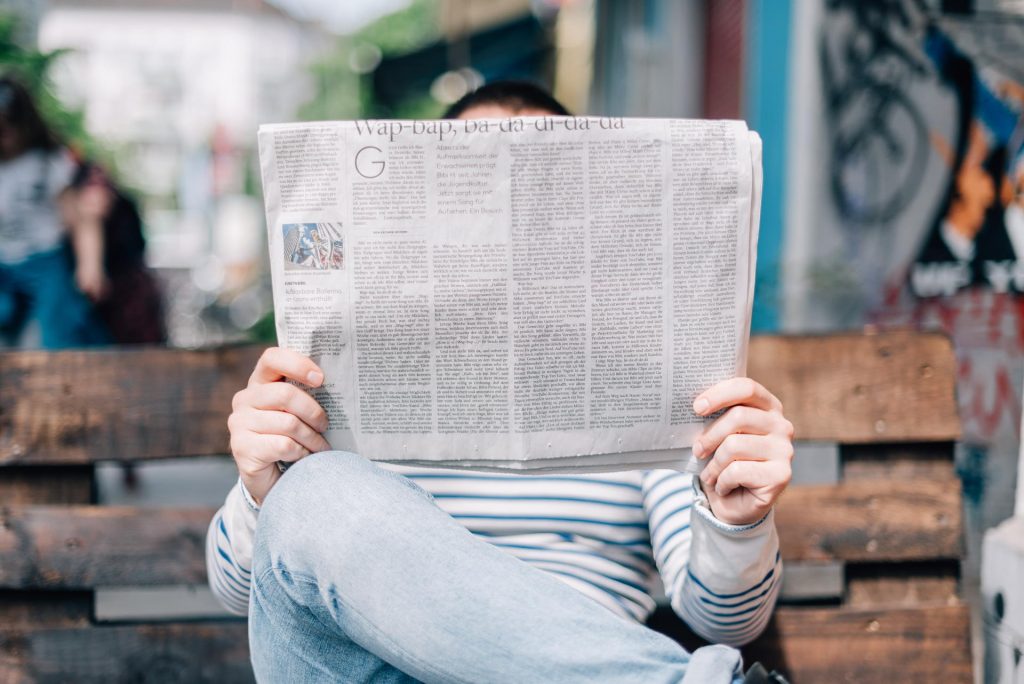 Image of man reading a newspaper to direct to news page